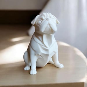 K&ouml;nnte beinhalten: Eine wei&szlig;e Keramikfigur eines Mops-Hundes in sitzender Position. Der Mops hat ein detailliertes, geometrisches Design mit sichtbaren Falten und Knicken. Die Figur steht auf einer hellen Holzoberfl&auml;che.