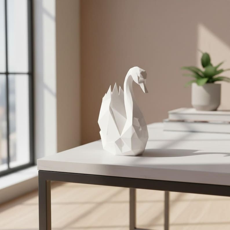 May include: A white geometric swan sculpture with a modern design. The swan is made of multiple triangular and rectangular shapes, creating a faceted appearance. The sculpture is placed on a white table with a black metal frame.