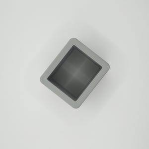 Pu&ograve; includere: Un contenitore quadrato grigio con interno incassato. Il contenitore ha una finitura liscia e opaca ed &egrave; posto su uno sfondo bianco. Il design &egrave; semplice e moderno, con linee pulite e un'estetica minimalista.
