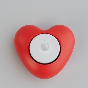 May include: A red heart-shaped candle holder with a white candle. The candle holder is a solid, vibrant red, and the candle is white with a small, flame-shaped top. The design is simple and modern.