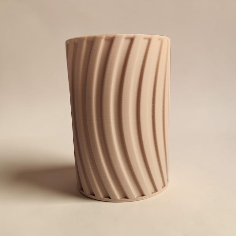 May include: A set of three ceramic mugs with a speckled, matte finish. The mugs are in shades of cream, light gray, and dark gray. Each mug has a simple, minimalist design and a rounded handle.
