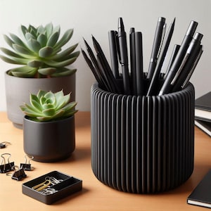 May include: A black, ribbed pen pot filled with black pens and pencils. Two potted succulents and a small black tray with paper clips are also on the wooden surface. The office supplies are arranged on a light brown wooden desk.