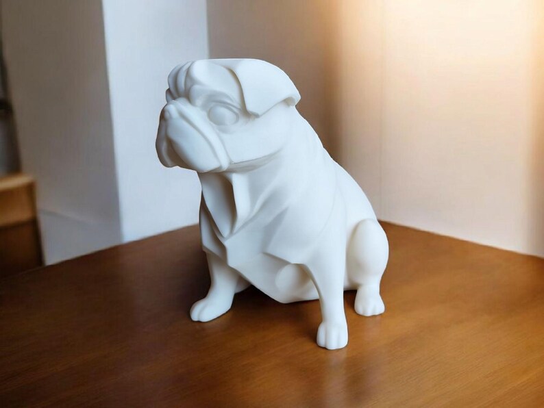 K&ouml;nnte beinhalten: Eine wei&szlig;e Mops-Hundeskulptur mit einem stilisierten, geometrischen Design. Der Hund sitzt auf einer Holzoberfl&auml;che. Die Skulptur hat eine glatte Oberfl&auml;che und ist ein dekorativer Gegenstand.