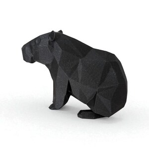 May include: A black geometric sculpture of a capybara, a large rodent. The sculpture has a faceted, low-poly design, giving it a modern and artistic look. The capybara is depicted in a seated position, with its head turned slightly to the side.