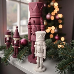 May include: A collection of decorative nutcrackers in various sizes and colors, arranged on a windowsill. The nutcrackers are primarily burgundy and white, with intricate details. A Christmas tree with ornaments and lights is visible in the background, along with evergreen branches.