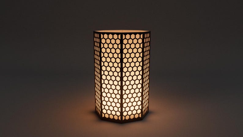 Op de afbeelding: Een cilindervormige lamp met een honingraatpatroon. De lamp is gemaakt van donkerbruin materiaal en straalt een warm, zacht licht uit. Het geometrische ontwerp cre&euml;ert een visueel aantrekkelijk effect, geschikt voor interieurdecoratie.