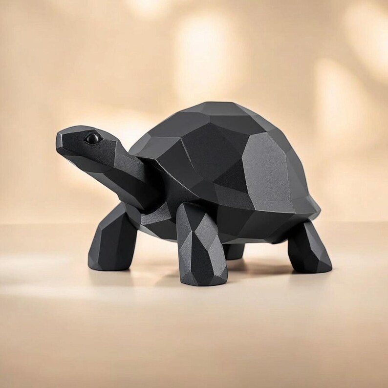 May include: A black geometric turtle sculpture with a faceted design. The turtle has a detailed head, four legs, and a shell. The sculpture is made of a solid material and is displayed on a neutral surface.