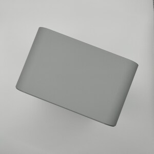 May include: A solid gray lampshade with a curved rectangular shape. The lampshade is made of a smooth material and has rounded corners. The neutral color makes it suitable for various interior design styles.