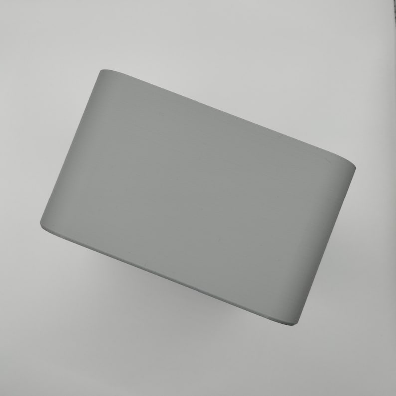 May include: A solid gray lampshade with a curved rectangular shape. The lampshade is made of a smooth material and has rounded corners. The neutral color makes it suitable for various interior design styles.