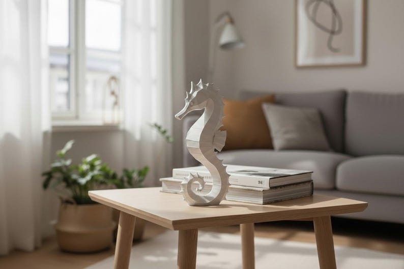 May include: A white seahorse sculpture sits on a light wood square table. The seahorse is the focal point, with a detailed, textured design. The table is in a living room setting, with books and a sofa in the background.