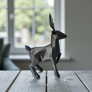 May include: A geometric, black deer sculpture with a modern design. The deer is posed mid-stride, with its antlers and body constructed from angular, faceted shapes. The sculpture is displayed on a light-colored wooden surface.