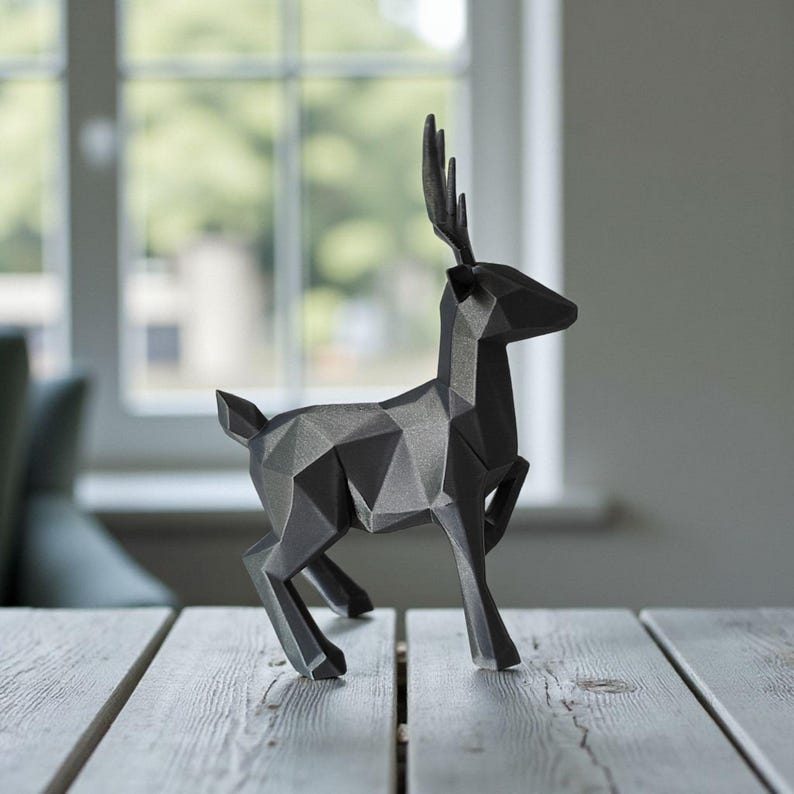 May include: A geometric, black deer sculpture with a modern design. The deer is posed mid-stride, with its antlers and body constructed from angular, faceted shapes. The sculpture is displayed on a light-colored wooden surface.