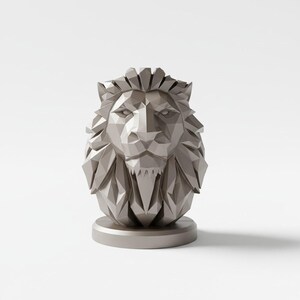 May include: A geometric, metallic lion head sculpture in a neutral gray color. The lion's mane and face are composed of angular facets, giving it a modern, stylized appearance. The sculpture sits on a circular base, creating a balanced and elegant design.