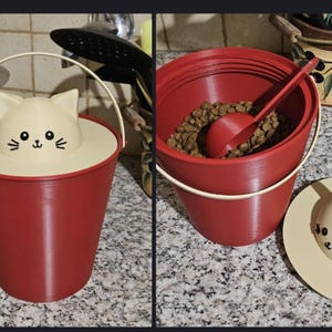 May include: Red cat-themed pet food container with a cream-colored lid featuring a cat face. The container has a metal handle and a matching scoop. The container is filled with pet food.