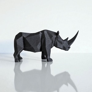 May include: A black, geometric rhino sculpture with a textured surface. The rhino has a large horn and is standing on a reflective surface. The sculpture's design features many flat planes, giving it a modern look.