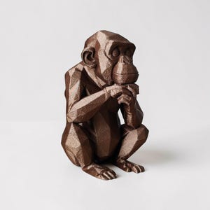 May include: A brown geometric chimpanzee sculpture in a seated position, with hands clasped near its mouth. The sculpture has a faceted design, giving it a modern, angular appearance. The chimpanzee is on a white background.