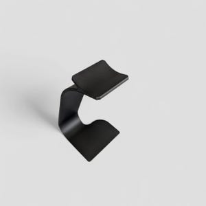 Peut inclure: Un support en m&eacute;tal noir minimaliste avec un design incurv&eacute;. Le support pr&eacute;sente un dessus plat et rectangulaire et une base incurv&eacute;e, cr&eacute;ant une esth&eacute;tique moderne et &eacute;l&eacute;gante. Le support est con&ccedil;u pour contenir un objet.