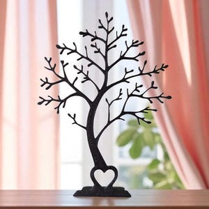 May include: A black metal jewelry tree shaped like a tree with a heart-shaped base. The tree has many branches for hanging necklaces, bracelets, and earrings. The background includes a window and pink curtains.