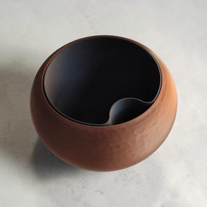 May include: A set of three ceramic mugs with a speckled, matte finish. The mugs are in shades of cream, light gray, and dark gray. Each mug has a simple, minimalist design and a rounded handle.