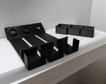 May include: Four black plastic shelf brackets with a hook on the end. The brackets are designed to hold items on a shelf.