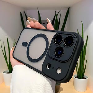 Puede incluir: Una funda de tel&eacute;fono negra y transparente con un dise&ntilde;o circular y un protector de lente de c&aacute;mara. La funda tiene un acabado mate y un borde negro. El protector de lente de la c&aacute;mara tiene tres lentes.