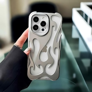 May include: A silver phone case with a clear back and a flame design. The case has a raised edge around the camera lenses.