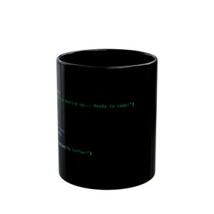 Op de afbeelding: Zwarte koffiemok met groene tekst die luidt "is booting up... Ready to code!" en "No Coffee!". De mok is cilindrisch en lijkt van keramiek te zijn.