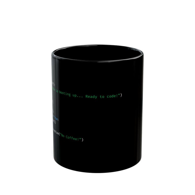 Op de afbeelding: Zwarte koffiemok met groene tekst die luidt "is booting up... Ready to code!" en "No Coffee!". De mok is cilindrisch en lijkt van keramiek te zijn.