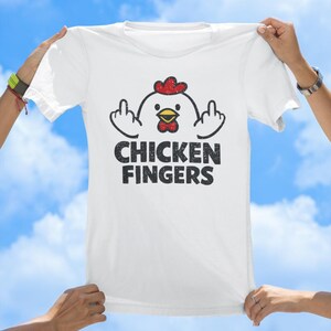 May include: A white short-sleeved t-shirt featuring a graphic of a cartoon chicken with a red comb and yellow beak, holding up its middle fingers on both sides. Below the chicken, the text CHICKEN FINGERS is printed in a distressed black font.