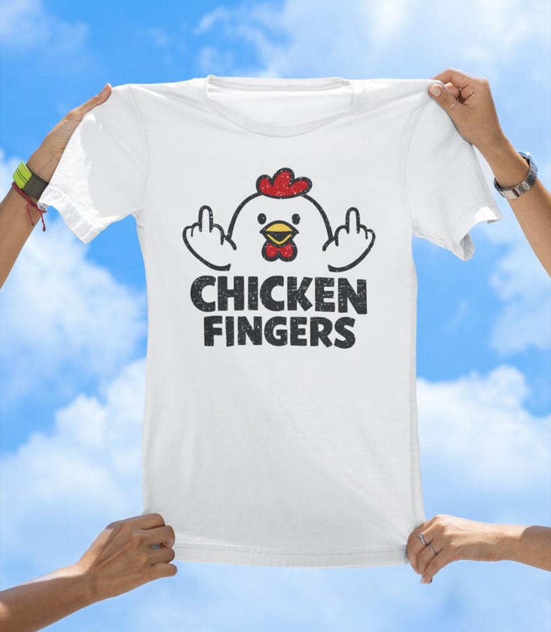 May include: A white short-sleeved t-shirt featuring a graphic of a cartoon chicken with a red comb and yellow beak, holding up its middle fingers on both sides. Below the chicken, the text CHICKEN FINGERS is printed in a distressed black font.