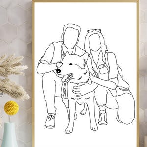 May include: A framed black and white line art print featuring a couple and their dog. The artwork depicts the couple embracing the dog, with the dog positioned in the center. The print is in a gold frame and is displayed on a white surface.