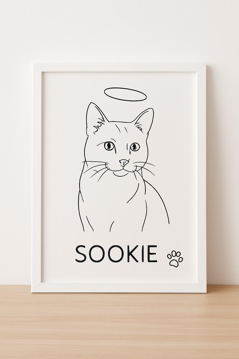 May include: A framed art print featuring a black and white line drawing of a cat with a halo. The cat's name, "SOOKIE," is printed below, along with a paw print. The artwork is set against a white background.