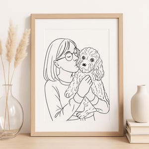 May include: A framed black and white line art print featuring a person kissing a dog. The person is wearing glasses and a long-sleeved shirt. The dog has curly fur. The frame is light brown.