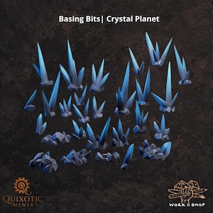 May include: A collection of miniature basing bits labeled Basing Bits | Crystal Planet, featuring various clusters of sharp, pointed blue crystals emerging from dark grey rocky bases, designed for tabletop gaming terrain and model decoration.