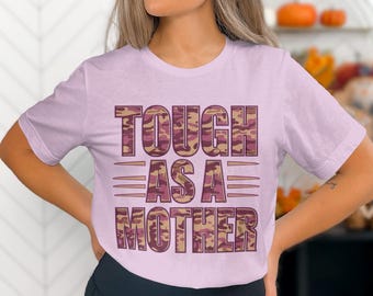 May include: A pink t-shirt with a camouflage print design that says "Tough as a Mother" in brown letters.