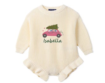 May include: A cream-colored long-sleeve knit romper with a ribbed texture and ruffled leg openings. The center features a graphic of a pink car carrying a Christmas tree on its roof, with the name Isabella printed in dark green script below.
