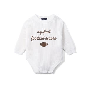 May include: A white long-sleeve knit bodysuit featuring the brown text 'my first football season' centered on the chest above a brown and white football graphic. The garment has a ribbed texture, a crew neckline, and metal snap closures at the base.