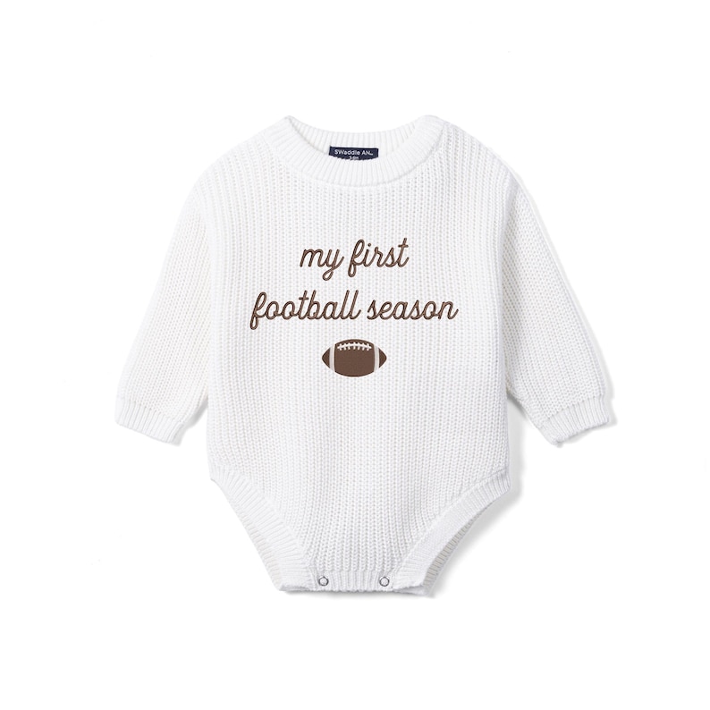 May include: A white long-sleeve knit bodysuit featuring the brown text 'my first football season' centered on the chest above a brown and white football graphic. The garment has a ribbed texture, a crew neckline, and metal snap closures at the base.