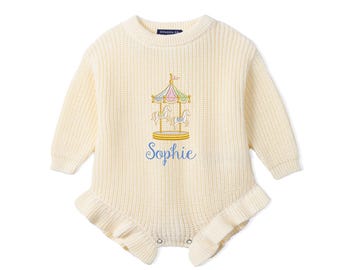 May include: A cream-colored long-sleeve knit romper featuring a ribbed texture and ruffled leg openings. The center of the chest displays an embroidered carousel graphic with pastel accents and the name Sophie stitched in blue script lettering.