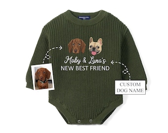 May include: An olive green long-sleeve knit romper featuring a graphic of two dogs and the white text Moby & Luna's NEW BEST FRIEND. A small inset photo shows a brown dachshund, and a box with an arrow points to the text CUSTOM DOG NAME.