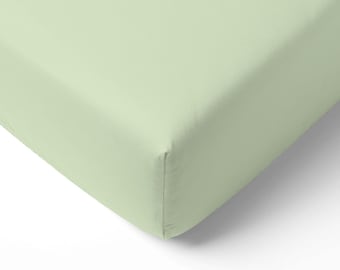 May include: A pale green fitted sheet, with a smooth texture. The sheet is a solid colour and appears to be made of a lightweight fabric. The corner of the sheet is visible, showing a neatly sewn seam. The sheet is likely for a bed.