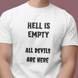 Puede incluir: Camiseta blanca con el texto "HELL IS EMPTY ALL DEVILS ARE HERE" en negrita, en negro. La camiseta es de cuello redondo y parece estar hecha de algodón. La camiseta la lleva una persona.