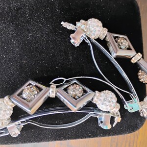 May include: Two silver-toned metal hair barrettes featuring a series of alternating clear crystal-encrusted spherical beads and smooth, diamond-shaped geometric frames. Each barrette has a hinged metal clasp mechanism for securing hair in place.