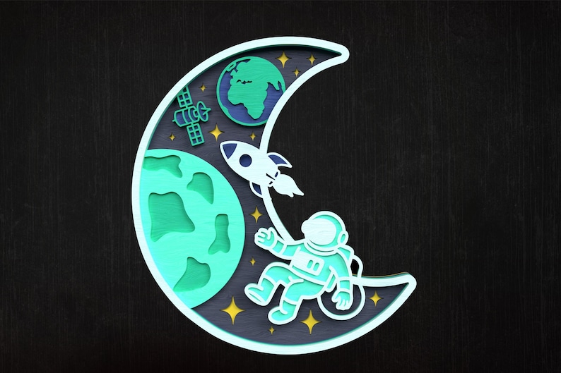 May include: A layered wooden artwork showing a space scene. A crescent moon shape frames an astronaut, rocket, Earth, and satellite. The artwork uses shades of blue, green, and yellow against a dark background.