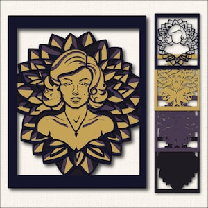 May include: A layered art piece featuring a stylized portrait of a woman with blonde hair, set against a gold and purple floral design. The artwork is framed in a dark blue border, with additional layered cutouts of the same design.