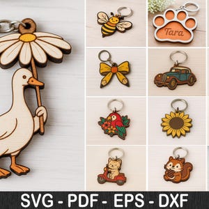 Könnte beinhalten: Holz-Schlüsselanhänger mit verschiedenen Designs: eine Ente mit Gänseblümchen-Schirm, eine Biene, ein Pfotenabdruck, ein Regenbogen, eine Schleife, ein Oldtimer, ein Flamingo, ein Papagei, eine Sonnenblume, ein Motorrad, eine Katze auf einem Roller, ein Eichhörnchen und eine Eule.