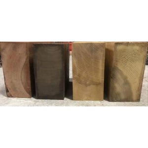 May include: Four wooden blocks of different colors and grain patterns. The blocks are arranged from left to right: reddish brown, dark brown, light brown, and light brown with a greenish tint.