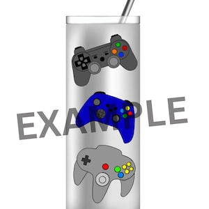 Puede incluir: Un vaso alto plateado con una pajita plateada, con tres diseños de mandos de videojuegos coloridos. Los mandos son grises y azules, con botones coloridos. La palabra "EXAMPLE" está impresa en el vaso.