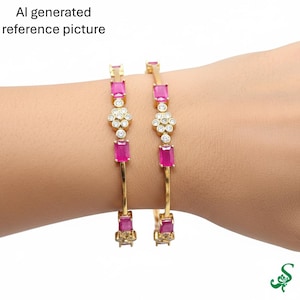 May include: Two gold bangles with pink rectangular and round white gemstone accents. The bangles are on a wrist. The text "AI generated reference picture" is in the upper left corner.