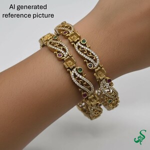 May include: Two gold-colored bangles with intricate floral and scrollwork designs. The bangles are adorned with clear and red gemstones, and a green gemstone. The text "AI generated reference picture" is in the upper left corner.